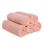 Five neatly rolled, light pink Natemia Organic Super Absorbent Washcloths made from 100% GOTS Certified Organic Cotton are stacked in a pyramid shape on a white background.