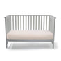 A gray toddler bed with slatted sides and back, paired with the Naturepedic Organic Breathable 2-Stage Baby Crib Mattress for a light-colored, breathable sleep surface.