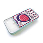 The Neighborgoods soy wax candle in an open rectangular reusable tin with a sliding lid featuring a fig graphic, the text Fig Candle, 100% Soy Wax, Fruity and Cozy with Notes of Amber, and a 4 oz / 113 g label.