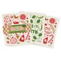 The Neighborgoods Happy Holidays Sponge Cloth Set featuring three eco-friendly Swedish sponge cloths with festive illustrations of a gingerbread man, candy cane, and citrus slices, labeled Seasons Eatings and Peas on Earth, in cardboard packaging.