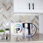 A New Wave Enviro Alkaline Pitcher Replacement Cartridge sits in its box on a kitchen counter with stacked glasses. In the background are white cabinets, a chevron-patterned backsplash, and a small plant.