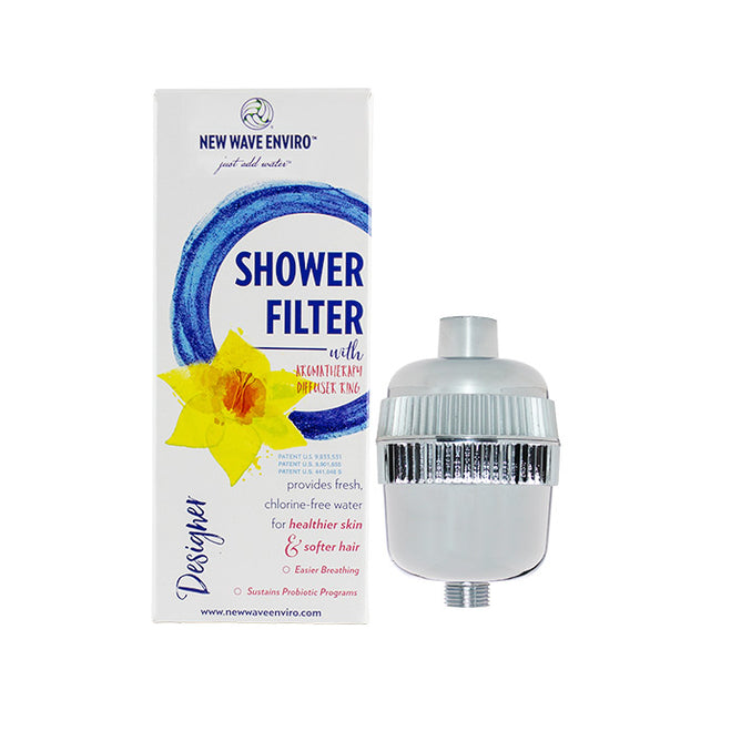 A New Wave Enviro Designer Shower Filter (silver) beside its box, featuring a yellow flower and blue circles. Highlights include reducing chlorine for healthier skin, softer hair, and easier breathing.