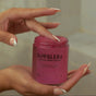 A person with manicured nails scoops NOPALERA’s Cactus Body Polish, a pink exfoliant, from an open jar.