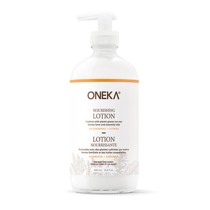 A clear plastic pump bottle labeled “Oneka Body Lotion - Goldenseal and Citrus” with gold accents displays both English and French text. This 16 fl oz (474 ml) organic lotion features deeply hydrating goldenseal, citrus, and ylang ylang.