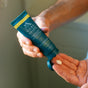 A person squeezes Oars + Alps Aluminum-Free Whole Body Cream Deodorant, made with natural starches for moisture absorption, from a blue tube onto their hand.