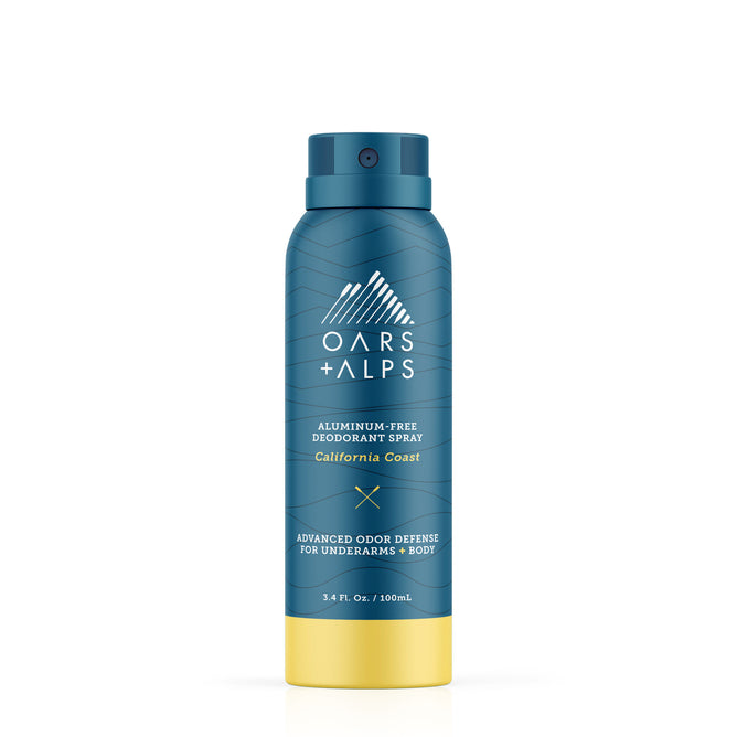 A blue and yellow can of Oars + Alps Spray Deodorant in California Coast scent, with white branding, offers advanced odor defense—ideal as a travel-size deodorant for freshening up on the go.