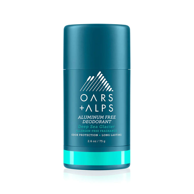 A teal stick of Oars + Alps Natural Deodorant, aluminum-free in a fresh ocean splash scent, features white text and a geometric mountain logo on the front. Net wt 2.6 oz (75 g).