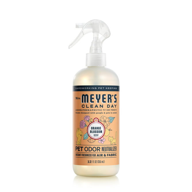 A 12-fluid ounce spray bottle of Mrs. Meyers Odor Neutralizer in Orange Blossom scent features a floral and pet-themed label, showcasing its powerful formula to eliminate pet odors in air and fabric.