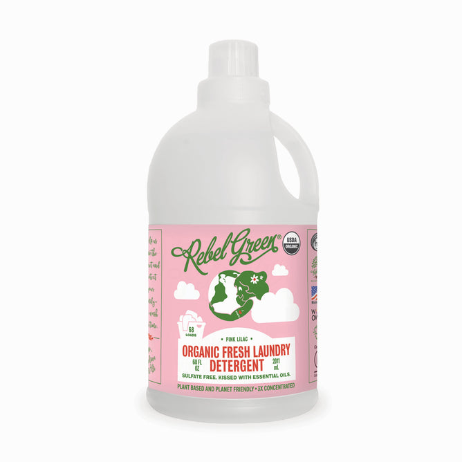 A white bottle of Rebel Green Fresh Laundry Detergent Liquid - 3x Concentrated with a pink label features a green woman hanging laundry. It offers a Pink Lilac scent, gentle ingredients, and is organic and cruelty-free certified.