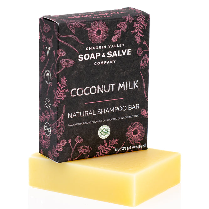 A yellow rectangular bar sits before a box labeled Chagrin Valley Soap & Salve Natural Shampoo Bar, made with organic coconut milk and coconut oil and featuring a floral design.