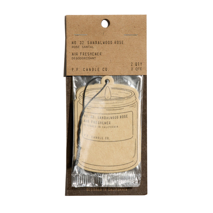 The P.F. Candle Co. Car Freshener in sandalwood rose scent comes in a clear plastic wrapper with a brown paper label, features a candle illustration, and instantly refreshes your space.