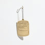 The P.F. Candle Co. Car Freshener, inspired by candle jars and featuring a No. 32: Sandalwood Rose scent, hangs from a black string on a hook against a white background, providing an eco-friendly fragrance with zero packaging waste.