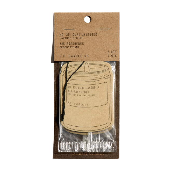 A P.F. Candle Co. Car Freshener, candle-jar shaped, delivers an instant scent boost. Packaged in brown kraft paper and clear plastic with product info on top, two Car Fresheners are visible inside.