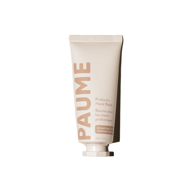 A beige tube of PAUME Probiotic Hand Balm stands upright on a white background, featuring English and French text. This hand balm provides lasting hydration for dry, chapped hands.
