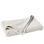 A light gray, neatly folded Coyuchi Air Weight® Organic Towel rests on a white surface, with one corner slightly lifted to reveal its soft and textured fabric.