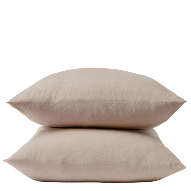 Two beige pillows stacked neatly on top of each other against a plain white background, each encased in Coyuchi’s Organic Crinkled Percale™ Pillowcases for a touch of natural comfort.