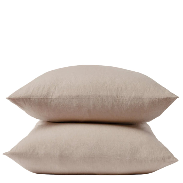 Two beige pillows stacked neatly on top of each other against a plain white background, each encased in Coyuchi’s Organic Crinkled Percale™ Pillowcases for a touch of natural comfort.