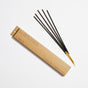 Four black Incense Sticks with yellow tips, infused with signature scents such as sandalwood, are arranged beside a long, rectangular brown paper box labeled "Golden Coast" and "P.F. Candle Co." on a white background.
