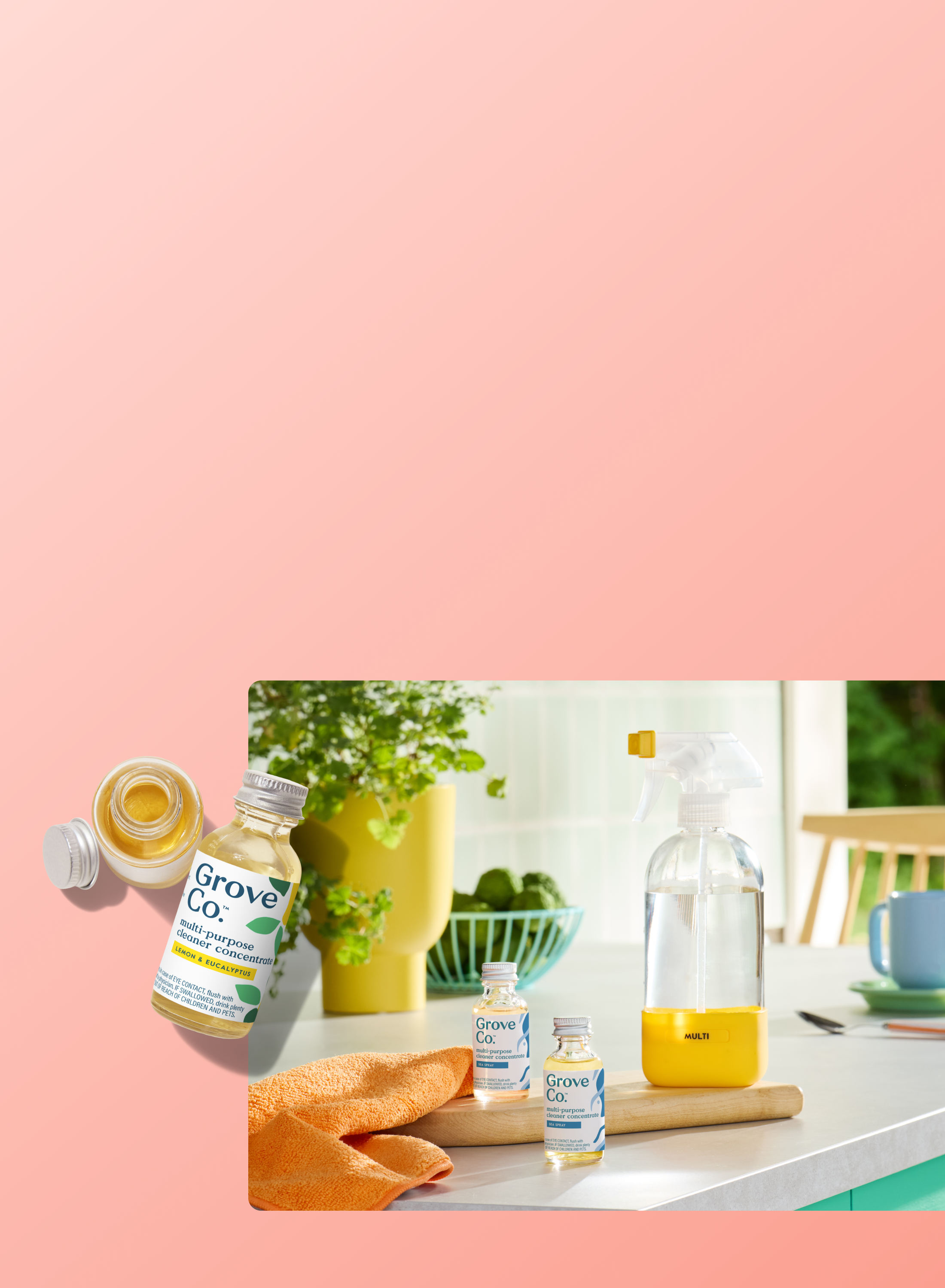 Grove Co. multi-purpose cleaner concentrate bottles in lemon & eucalyptus scent displayed alongside a reusable spray bottle on a bright kitchen counter with a plant and orange cloth.