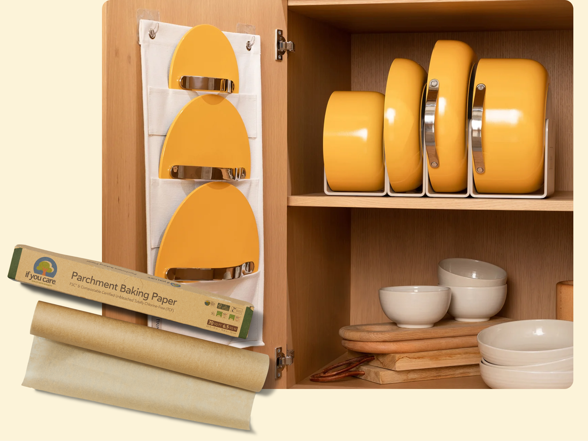 A kitchen cabinet displays yellow pans stored vertically, matching pan lids in a hanging organizer on the cabinet door, stacked white bowls, cutting boards, and a roll of parchment baking paper on the counter.
