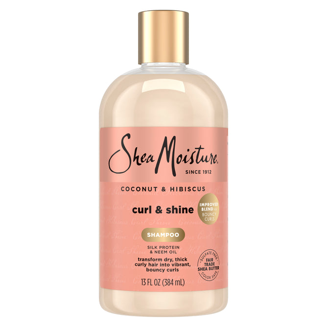 A 13 fl oz (384 mL) bottle of SheaMoisture Shampoo - Curl + Shine, featuring a peach label and gold cap, promotes frizz control and is specially formulated for thick, curly hair.