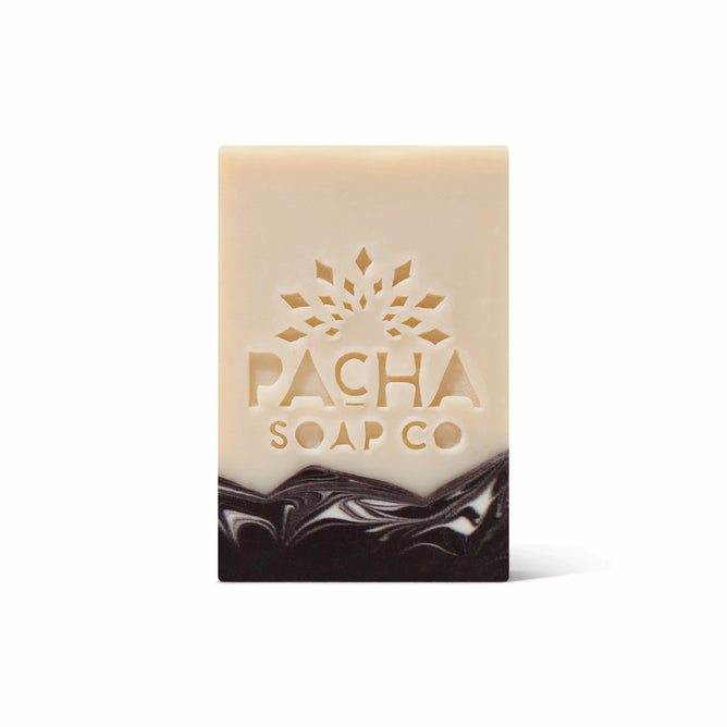 A rectangular, handcrafted Bar Soap by Pacha Soap Co. features a beige top, dark brown marbled bottom, and an embossed sunburst with the brand name. Made with nourishing oils. Presented on a plain white background.