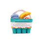The Fruit Basket Bath Bomb Set by Pacha Soap Co. is a small teal basket with a handle, holding kid-friendly banana-shaped bath bombs, two rolled towels, a purple fruit shape, and a label on the front.