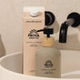 A Pacha Soap Co. Santal & Amber Hand Soap bottle with pump sits in a white sink beside a Pacha Soap Co. Hand Soap Refill carton, both made with shea butter and sustainably sourced palm oil; a black faucet is in the background.