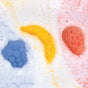 The Fruit Basket Bath Bomb Set by Pacha Soap Co. features blue raspberry, yellow banana, and red strawberry bath bombs that fizz in white water for vibrant colors. Kid-friendly and non-toxic, they make bathtime safe and fun.