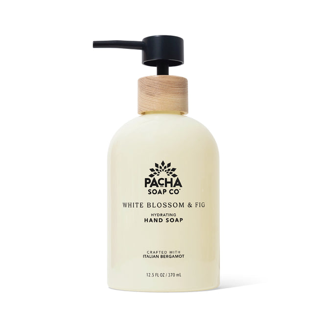 A 12.5 fl oz bottle of Pacha Soap Co. Liquid Hand Soap in White Blossom & Fig scent, featuring a black pump dispenser with wooden collar and enriched with shea butter.
