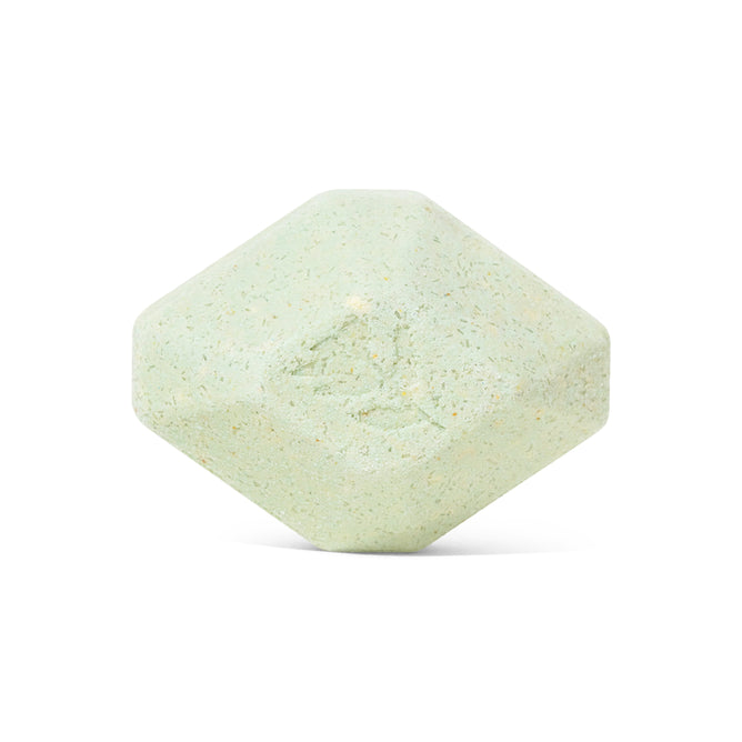 A pale green, hexagonal Muscle Therapeutic Bath Bomb by Pacha Soap Co. with gently rounded edges and a textured surface, shown against a white background—resembling an aromatherapy bath bomb.