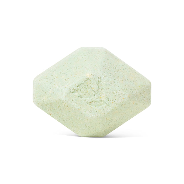 A pale green, hexagonal Muscle Therapeutic Bath Bomb by Pacha Soap Co. with gently rounded edges and a textured surface, shown against a white background—resembling an aromatherapy bath bomb.