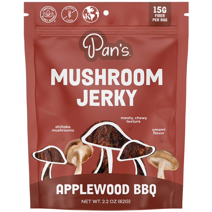 The vibrant red package of Pans Applewood BBQ Mushroom Jerky highlights 15G Fiber Per Bag, Vegan, Gluten Free, and Kosher symbols, featuring illustrations of shiitake mushrooms and textured jerky strips, reflecting its plant-based, savory flavor.