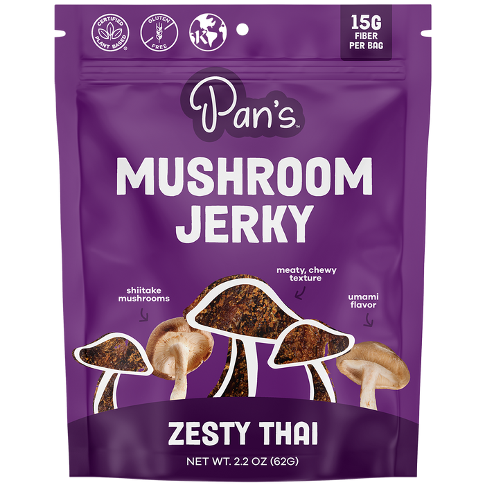 Pans Zesty Thai Mushroom Jerky, a vibrant purple bag, is ideal for vegan snack seekers. This gluten-free treat contains 15G fiber per bag and features images of shiitake mushrooms emphasizing its meaty, chewy texture with an umami flavor. Net wt. 2.2 oz (62g).