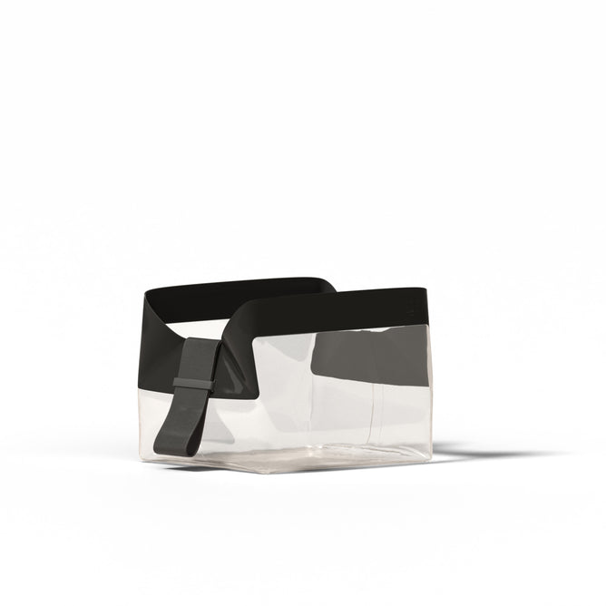 The Parcel by Cadence is a transparent, rectangular TSA-approved travel bag with black trim and an adjustable strap, designed by a women-owned AAPI brand, shown on a plain white background.