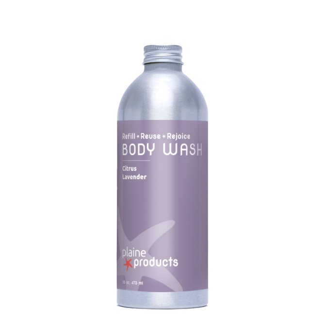 A silver aluminum bottle of Plaine Products Body Wash, Citrus Lavender, with a lavender label displaying "Refill • Reuse • Rejoice," "BODY WASH," and the Plaine Products logo for a skin-soothing experience.