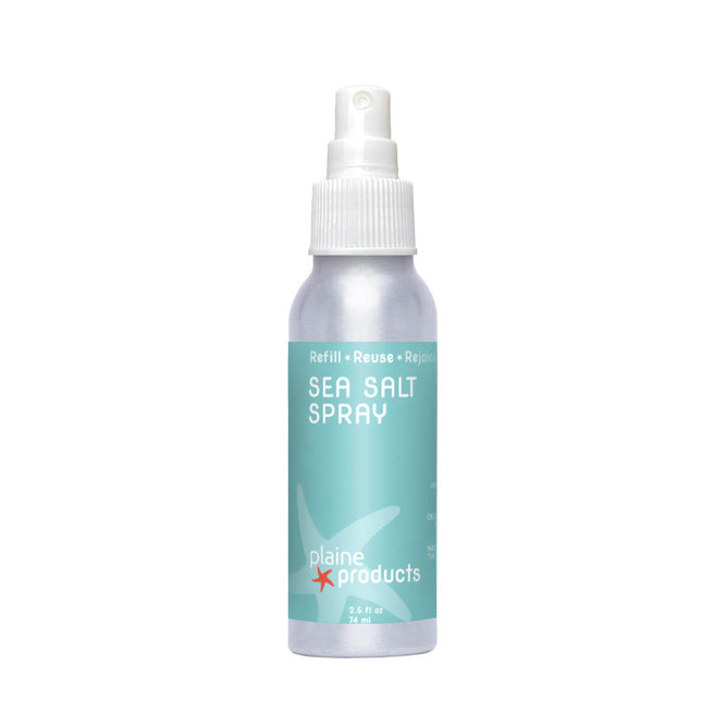 Plaine Products’ Sea Salt Spray comes in a silver bottle with a white spray cap and light blue-green label featuring a starfish and the words "Refill • Reuse • Rejoice," perfect for creating effortless, beach-inspired hair.