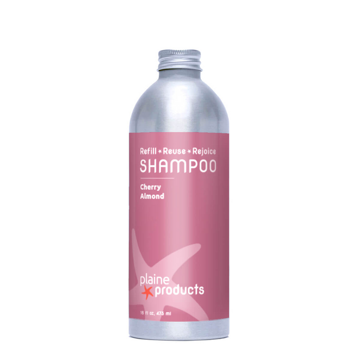 Plaine Products Shampoo, Cherry Almond, in a silver bottle with a pink label featuring "Refill • Reuse • Rejoice," is vegan and designed to add shine and reduce frizz for healthy, beautiful hair.