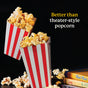Two red-and-white striped popcorn boxes are filled with popcorn tossed in Diaspora Spice Co.’s Popcorn Seasoning, with some kernels spilling over. Nearby, books are stacked. Text reads: Better than theater-style popcorn. The background is black.