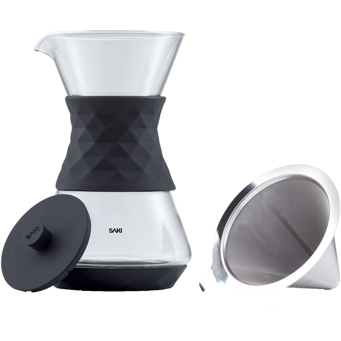 A SAKI Pour-Over Glass Coffee Maker featuring a diamond-patterned black silicone sleeve is displayed with a matching black lid and a stainless-steel mesh filter placed beside it.