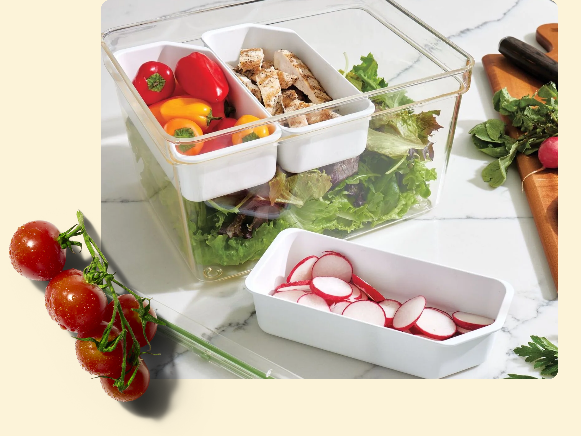 A clear container holds fresh leafy greens with two small white trays on top, one with sliced grilled chicken and mini bell peppers. Nearby, a tray of sliced radishes and a vine of cherry tomatoes rest on the countertop.