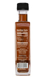 A square glass bottle of Runamok Infused Maple Syrup - Pumpkin Spice, filled with amber liquid, features a nutrition label, ingredients list, and a barcode at the bottom.