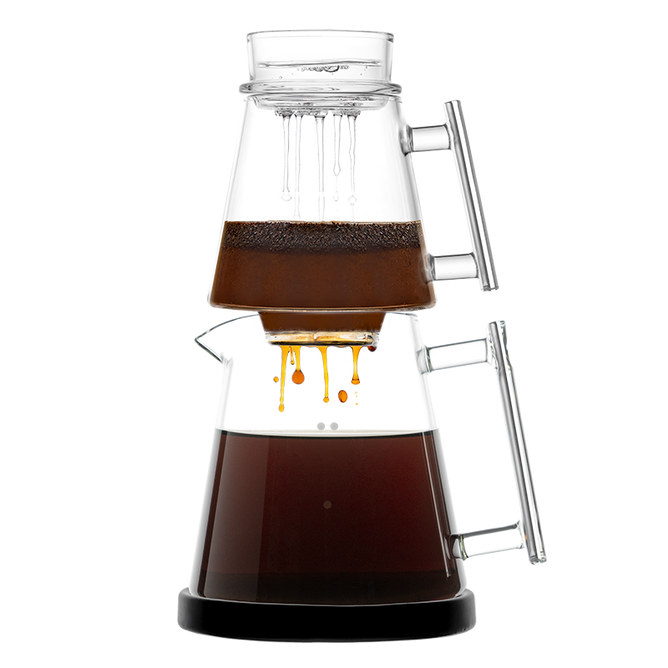 The Pure Over Signature Brew Kit is a pour-over coffee maker with two stacked glass chambers and handles; the top holds grounds and water while brewed coffee drips into the lower carafe, set against a white background.