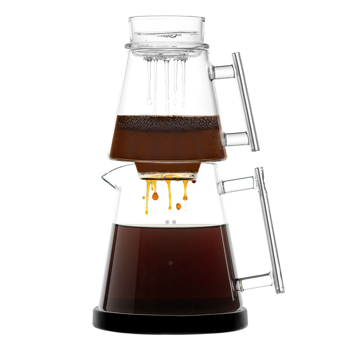 The Pure Over Signature Brew Kit is a pour-over coffee maker with two stacked glass chambers and handles; the top holds grounds and water while brewed coffee drips into the lower carafe, set against a white background.