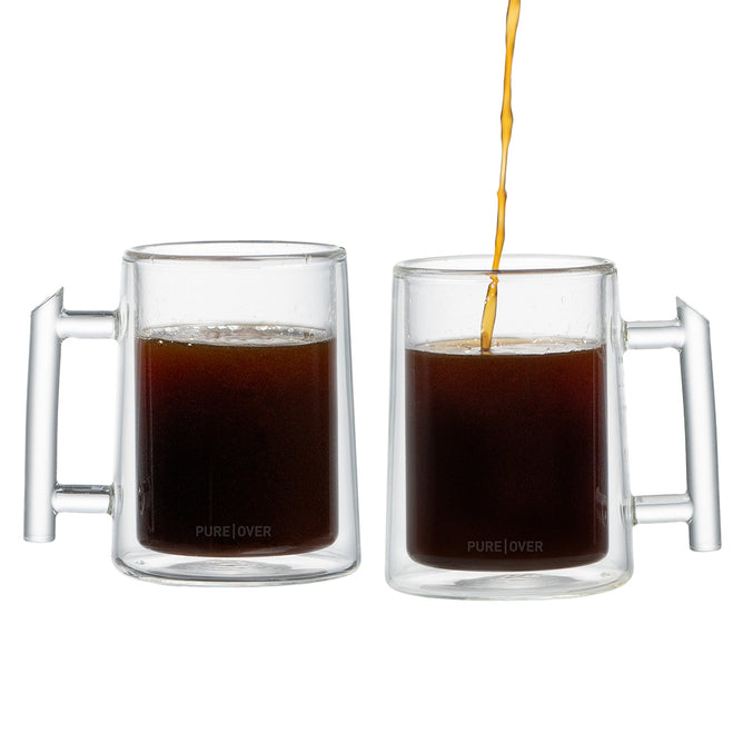 Two Pure Over Double-Walled Mug Set mugs, each with a sturdy handle, are filled with dark coffee—one already full as coffee pours into the other. Perfect for your daily brew.