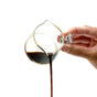 A hand pours dark coffee from the Pure Over Espresso Measuring Cup, made of borosilicate glass with a spout, against a plain white background—perfect for any barista.