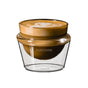 The Pure Over Cortado Cup (5 oz) is a double-walled borosilicate glass cup with branding, shown on a white background holding a cappuccino topped with heart-shaped latte art.