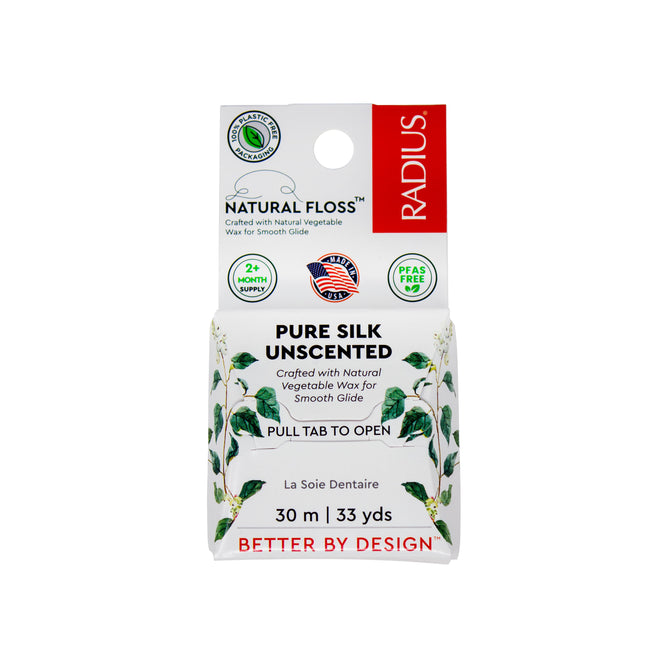 Front view of a Radius Natural Silk Floss box labeled Pure Silk Unscented, featuring a green leaf design, environmental certifications, and a red “Better by Design” tagline at the bottom. This plastic-free dental floss from Radius is crafted from natural silk for an eco-friendly clean.