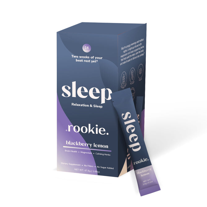A box labeled Sleep Powder Packets, Relaxation & Sleep by Rookie Wellness, blackberry lemon flavor, with a stick pack beside it. The dark blue and purple packaging highlights melatonin and magnesium for relaxation, sleep, and brain health.