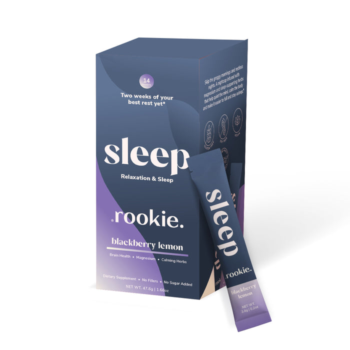 A box labeled Sleep Powder Packets, Relaxation & Sleep by Rookie Wellness, blackberry lemon flavor, with a stick pack beside it. The dark blue and purple packaging highlights melatonin and magnesium for relaxation, sleep, and brain health.